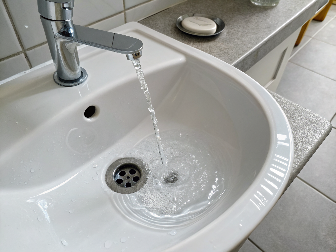 Professional plumber clearing a clogged bathroom sink drain and removing debris